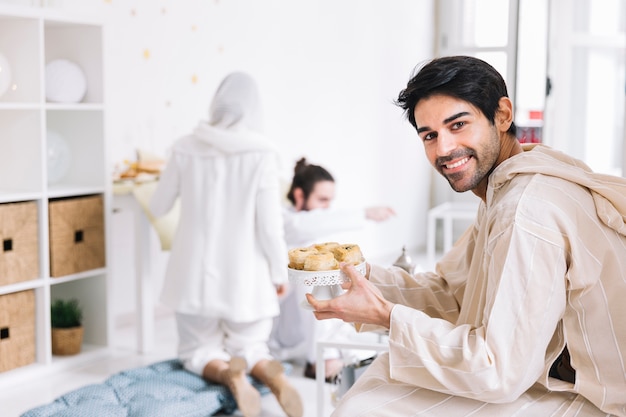 Concepto de eid al-fitr con hombre presentando pasteles árabes