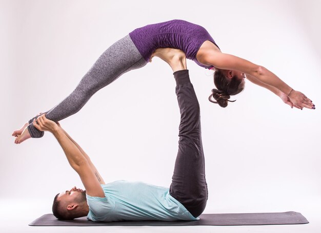 Concepto de ejercicios de Yoga. Pareja joven sana en posición de yoga sobre fondo blanco.