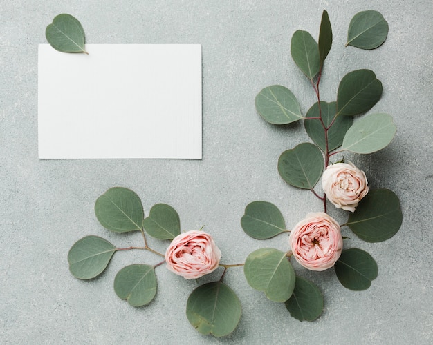 Concepto elegante de hojas y rosas con tarjeta vacía