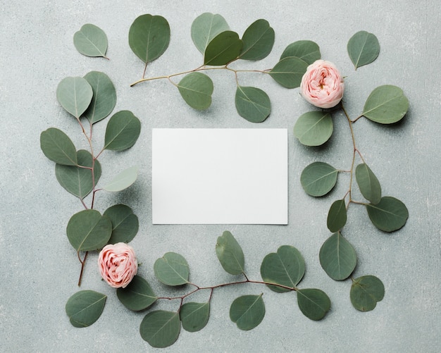 Concepto elegante marco de hojas y rosas con tarjeta vacía