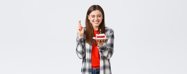 Concepto de emociones de celebración y vacaciones de estilo de vida de personas Feliz cumpleaños alegre niña celebrando cerrar los ojos cruzar los dedos como soplar una vela para pedir un deseo en el pastel de cumpleaños