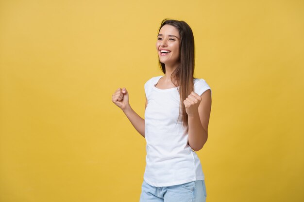 Concepto de emociones, expresiones, éxito y personas - feliz joven o adolescente celebrando la victoria aislada sobre fondo amarillo.