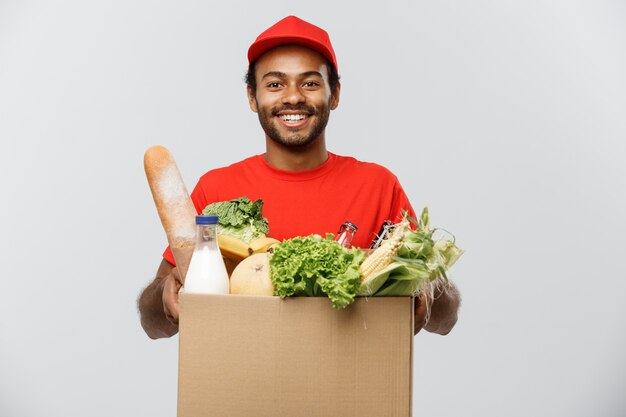 Concepto de entrega - African American hombre de entrega hermosa llevar paquete de alimentos y bebidas de supermercado de la tienda. Aislado en el estudio de fondo gris. Espacio De La Copia.