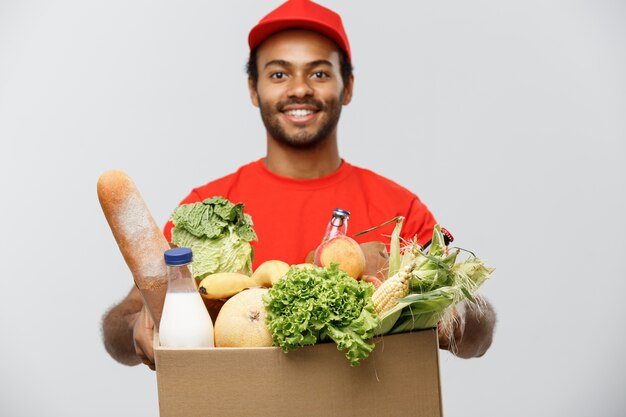 Concepto de entrega - African American hombre de entrega hermosa llevar paquete de alimentos y bebidas de supermercado de la tienda. Aislado en el estudio de fondo gris. Espacio De La Copia.