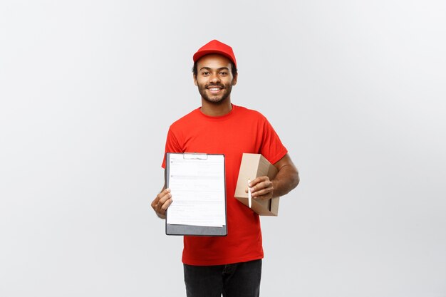 Concepto de entrega - Retrato de hermoso African American entrega hombre o mensajero mostrando un formulario de documento de confirmación de firmar. Aislado en el estudio de fondo gris. Espacio De La Copia.