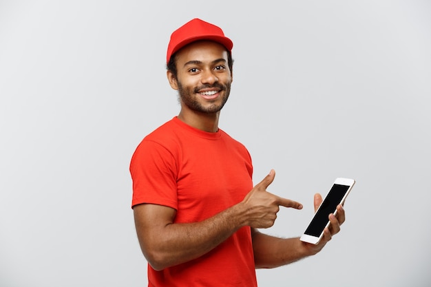 Concepto de entrega - Retrato de hermoso African American hombre de entrega o mensajero con cuadro que muestra la tableta sobre usted para comprobar la orden. Aislado en el estudio de fondo gris. Espacio De La Copia.