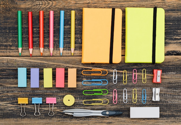 Concepto de escuela con cuadernos, útiles escolares en mesa de madera plana lay.