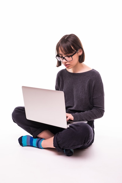 Concepto de escuela, educación, internet y tecnología - joven adolescente sentada en el suelo con ordenador portátil