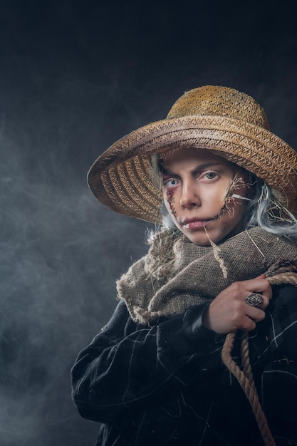 Concepto de espantapájaros malvado y espeluznante - mujer joven en niebla y humo está posando para el fotógrafo.