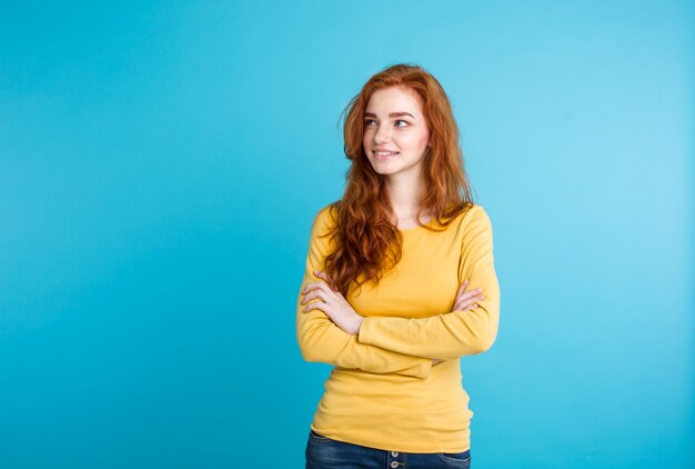 Concepto de estilo de vida - Close up Retrato joven hermosa atractiva jengibre pelo rojo chica jugando con su cabello con timidez. Fondo De Pastel Azul. Copie el espacio.