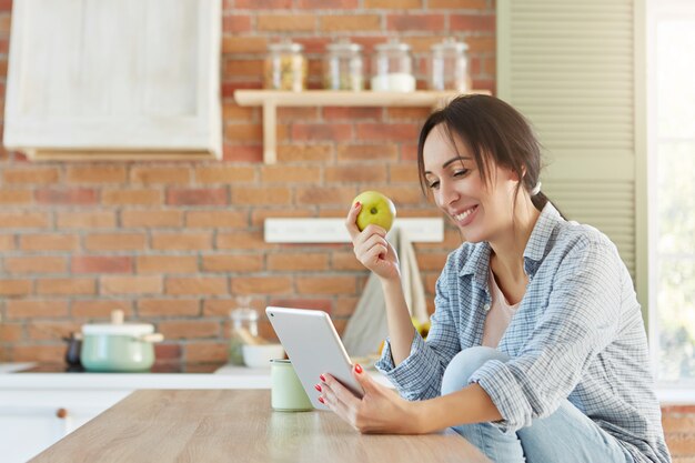 Concepto de estilo de vida y comida sana. Bonita hembra come manzana, busca nueva dieta en internet,