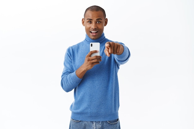 Concepto de estilo de vida en línea de tecnología Retrato de un hombre afroamericano entretenido y divertido viendo algo increíble grabar un video apuntando a algo genial tomando fotos en el fondo blanco del teléfono inteligente