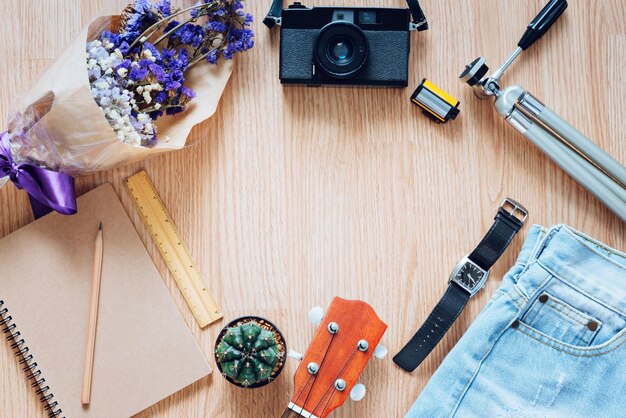 Concepto de estilo de vida con nota de viaje y accesorios de fotografía de cine con atuendos casuales estilo plano sobre fondo de madera con espacio de copia