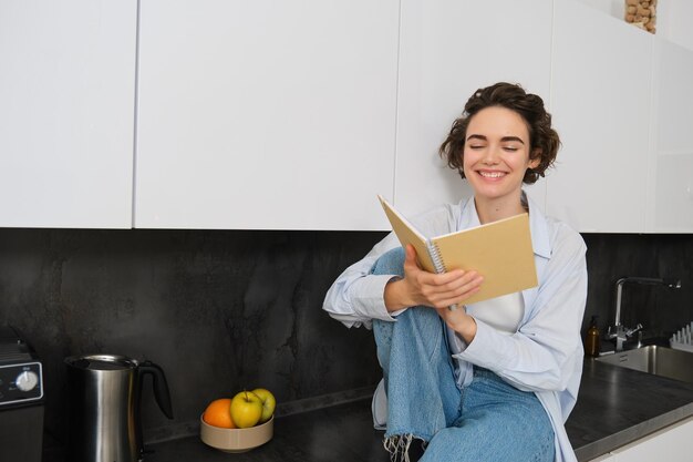 Concepto de estilo de vida y personas mujer joven disfrutando el fin de semana en casa leyendo notas en su diario se sienta