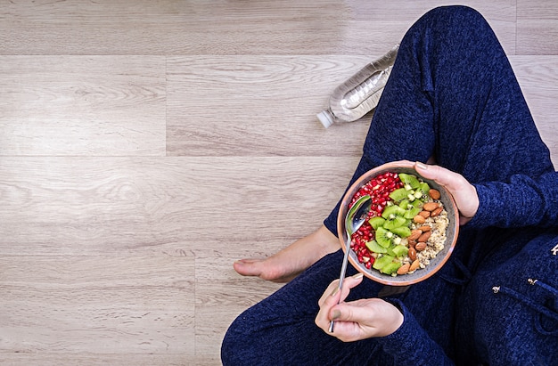 Concepto de estilo de vida saludable y fitness. la mujer está descansando y comiendo una avena saludable después de un entrenamiento. vista superior.