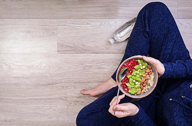 Concepto de estilo de vida saludable y fitness. La mujer está descansando y comiendo una avena saludable después de un entrenamiento. Vista superior.