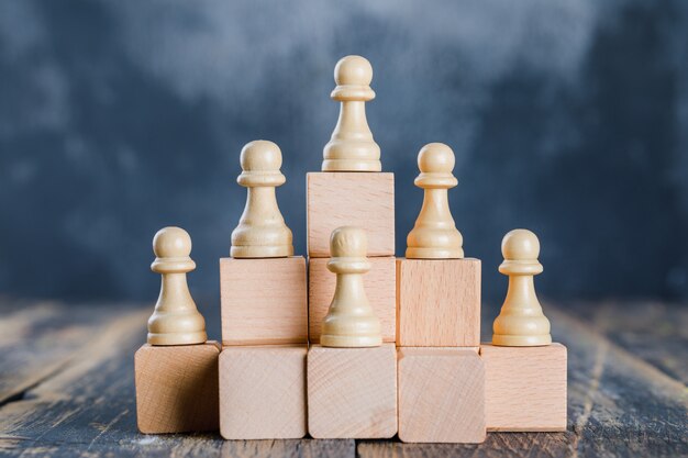 Concepto de estrategia empresarial con figuras de ajedrez en escaleras de madera de juguete