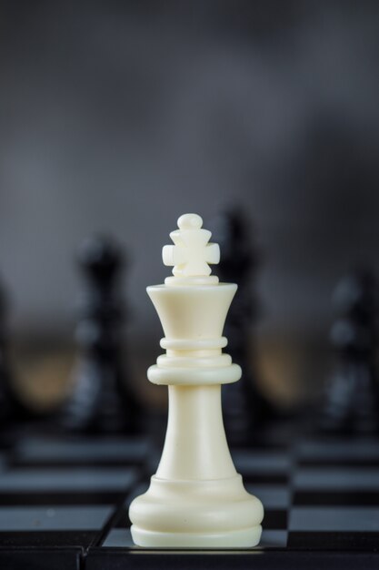 Concepto de estrategia empresarial con figuras en el tablero de ajedrez en primer plano de mesa borrosa y de madera.