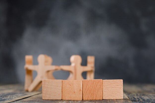 Concepto de éxito empresarial y trabajo en equipo con figuras de madera de personas, vista lateral de cubos.