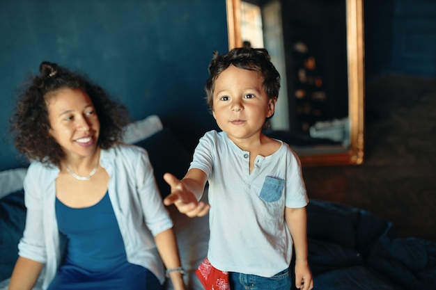 Concepto de familia, diversión, alegría, unión y ocio. Atractiva joven madre soltera hispana disfrutando de dulces momentos de maternidad