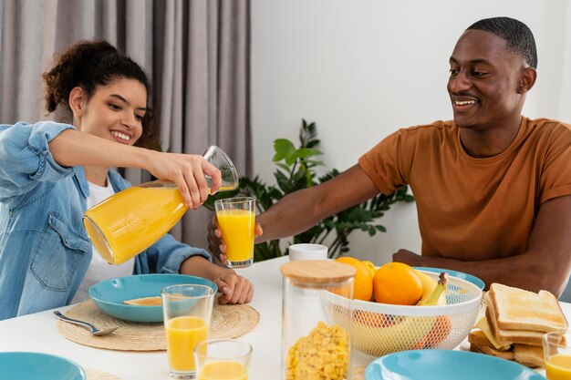 Concepto de familia negro feliz con jugo de pourinf mujer para socio