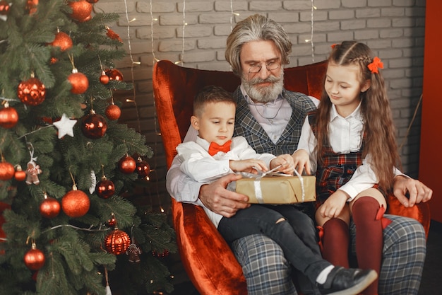 Concepto de familia, vacaciones, generación, navidad y personas. Niños en una habitación decorada para Navidad