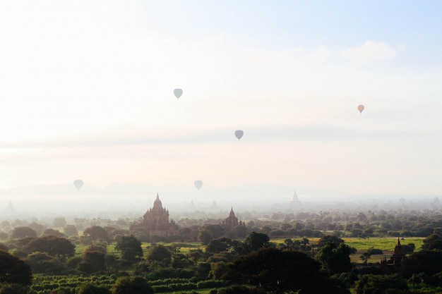 Concepto de fantasía: globos aerostáticos que vuelan sobre templos y castillos sobre un hermoso campo en el cielo