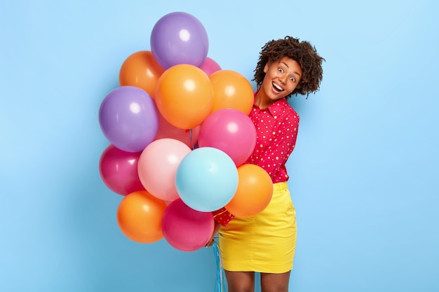 Concepto de felicidad y celebración. Mujer de piel oscura llena de alegría saluda a sus amigos con una ocasión especial