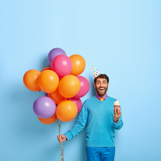 Foto gratuita concepto de feliz cumpleaños. sonriente hombre europeo tiene pastelito tasy