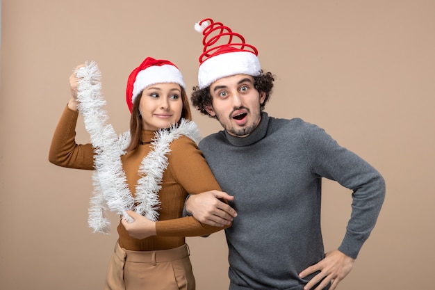 Concepto festivo de humor de año nuevo con una pareja encantadora satisfecha fresca emocionada con sombreros rojos de santa claus