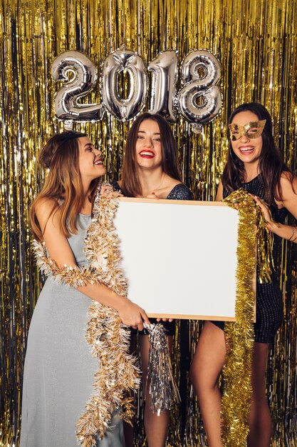 Concepto de fiesta de año nuevo con chicas enseñando pizarra blanca