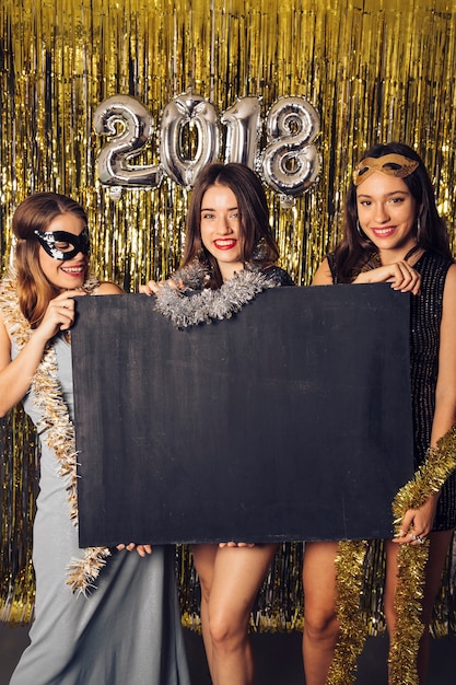 Concepto de fiesta de año nuevo con chicas mostrando pizarra