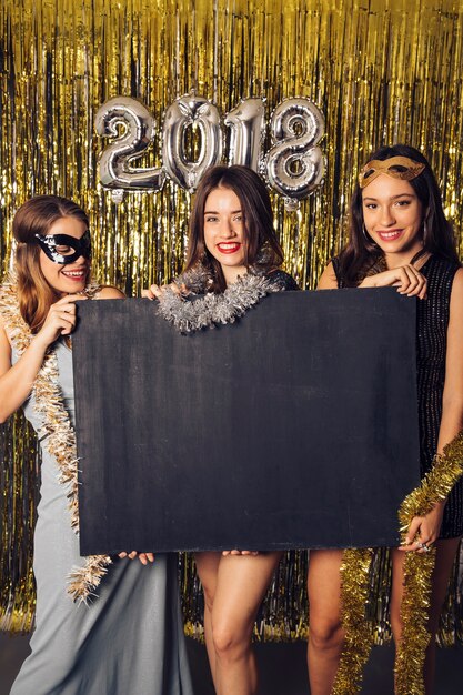 Concepto de fiesta de año nuevo con chicas mostrando pizarra