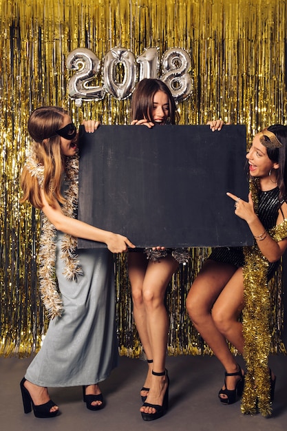 Foto gratuita concepto de fiesta de año nuevo con tres chicas presentando pizarra