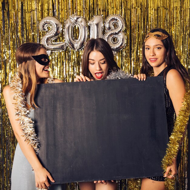 Concepto de fiesta de año nuevo con tres chicas y tabla