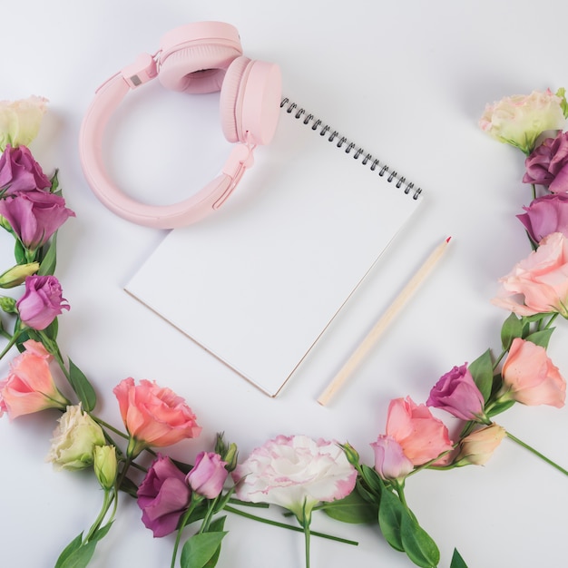 Concepto de flores con libreta y auriculares