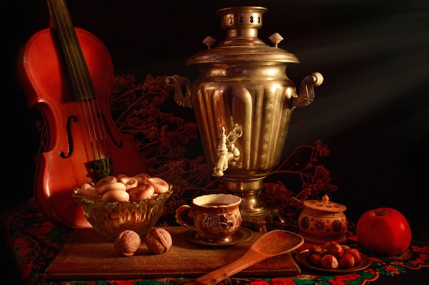 Concepto de fotografía de arte bodegón con samovar antiguo y violín aislado en un fondo negro