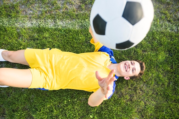 Concepto de fútbol de amateur con hombre tumbada tirando pelota