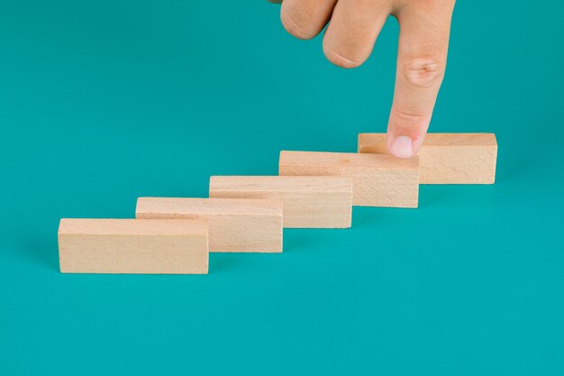 Concepto de gestión de negocios y riesgos en la vista de ángulo alto de la mesa turquesa. Dedo que muestra el bloque de madera.