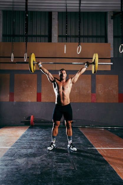 Foto gratuita concepto de gimnasio con hombre entrenando con barra de pesas