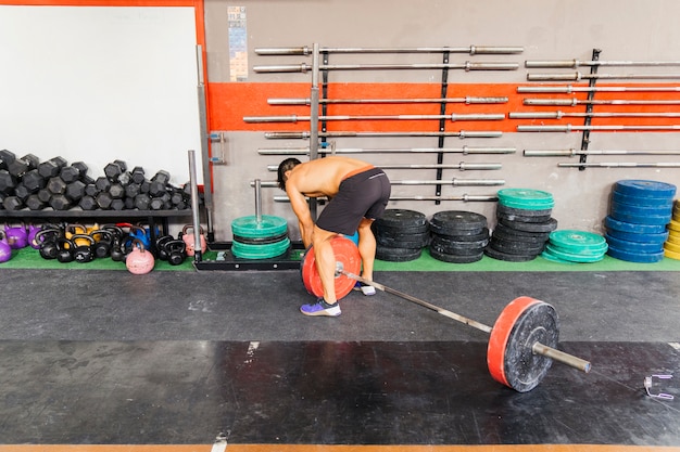 Concepto de gimnasio con hombre montando barra de pesas