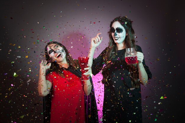 Concepto de halloween con mujeres, bebida y confeti