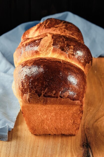 Concepto horneado de brioche francés tradicional Bollo de brioche orgánico hecho en casa fresco en el marco vertical de la vista superior de la mesa rústica Enfoque selectivo de primer plano