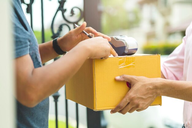 El concepto de ideas de entrega cierra el producto del paquete de la manija del mensajero indio al cliente con felicidad y entrada alegre a la puerta de la casa