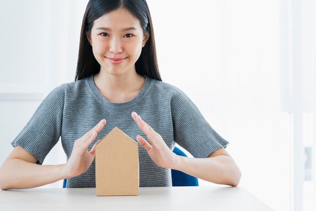 Foto gratuita concepto de ideas de seguros de negocios con mano de mujer asiática proteger modelo de papel de casa fondo blanco