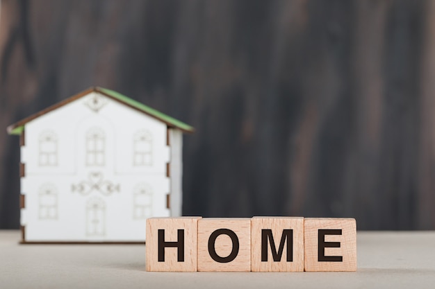 Concepto inmobiliario con cubos de madera, modelo de casa y blanco.