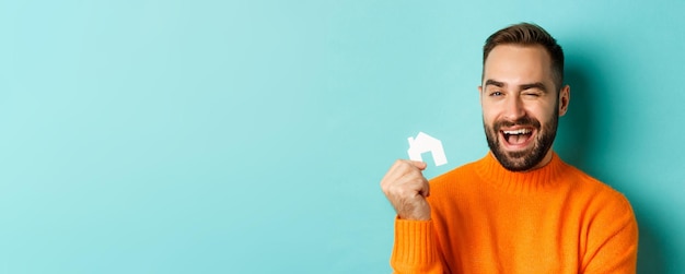 Concepto inmobiliario joven feliz buscando alquiler de casa sosteniendo el mercado de papel de la casa y sonriendo st