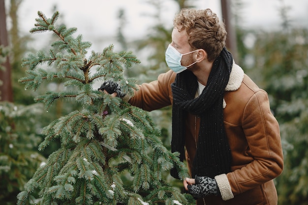 Concepto de invierno. Chico con un abrigo marrón. Vendedor de árbol de Navidad. Tema de coronavirus.