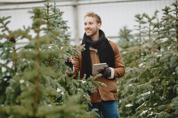 Concepto de invierno. Chico con un abrigo marrón. Vendedor de árbol de Navidad.