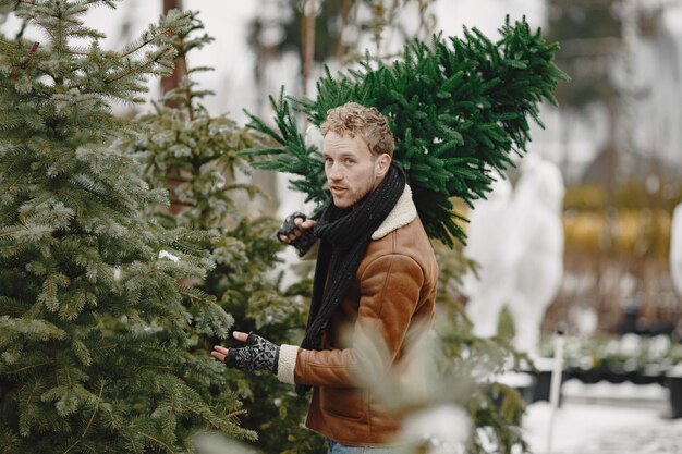 Concepto de invierno. Chico con un abrigo marrón. Vendedor de árbol de Navidad.
